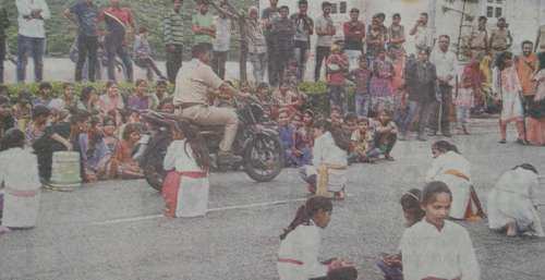 Policeman drives bike among children performing a play
