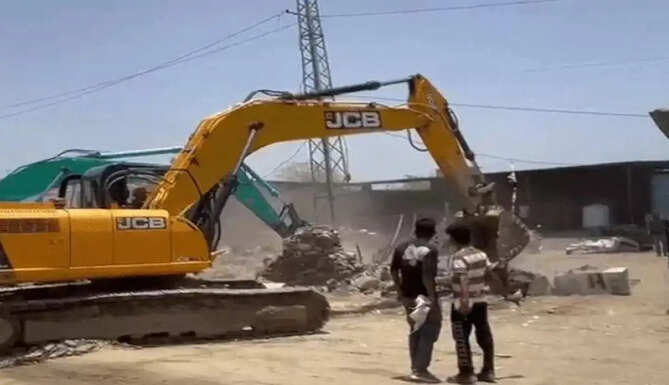 JCB machines removing illegal encroachments on acquired land along National Highway 162E between Bhatewar and Charbhuja Road in Vallabhnagar, Udaipur district.