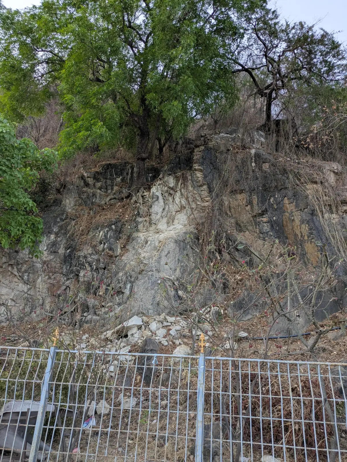Rocky hills near Fateh Sagar Lake in Udaipur showing visible cracks and potential landslide risk along the roadside.