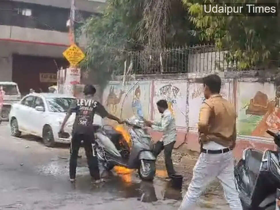 Alt Text: Scooter catches fire on Gulabbagh Road in Udaipur as locals extinguish flames