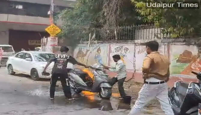 Alt Text: Scooter catches fire on Gulabbagh Road in Udaipur as locals extinguish flames